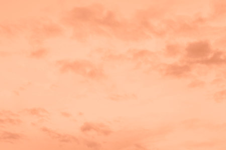 Peach Fuzz toned sky and clouds. Monochrome background 2024 color of the year.の写真素材