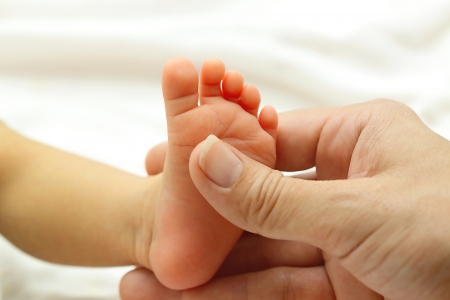 Mother massaging the foot of her small babyの写真素材
