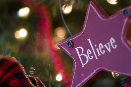 red star shaped believe ornament hanging on christmas treeの写真素材