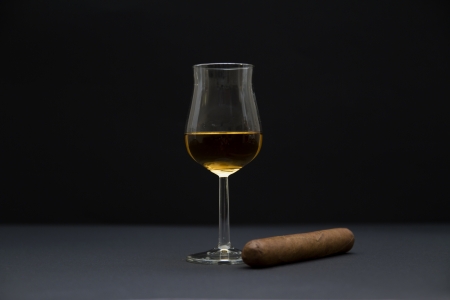 Side view of a robusto sized cigar and a glass of cognac  Dark background and shallow depth of fields の写真素材