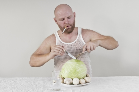 Wierd man eat cabbage and mushrooms while smoking a cigarette の写真素材