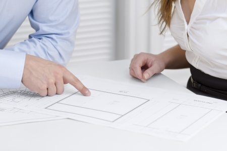 A businesswoman and a businessman in a meeting  Teamwork  Pointing and looking at a printed architect drawing on a table の写真素材