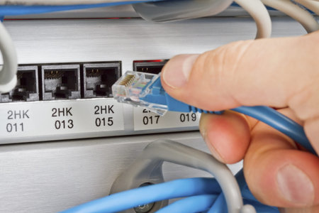 Close up of a IT consultant inserting   connecting a network   telephone cable into a patching panel...