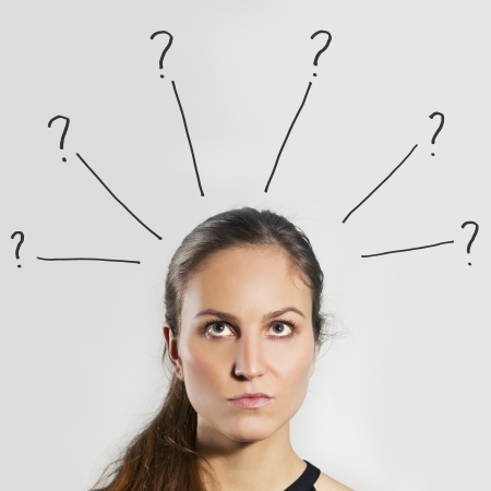 Young woman   girl thinking   wondering with gray background  Question marks over her head の写真素材