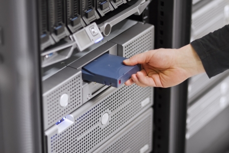 A close-up of a IT engineer   technician insert a backup tape in a backup robot in a rack  Shot in a data center の写真素材