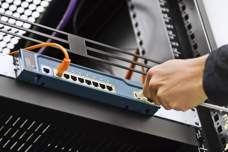 IT consultant inserting   connecting a network cable into a switch 