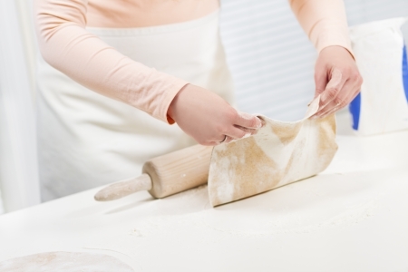Girl baking and roll dough  Making fajita or pizza  Spelt whole grain flour on the table の写真素材