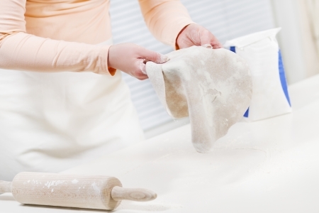 Girl baking and roll dough  Making fajitas or pizza  Spelt whole grain flour on the table の写真素材