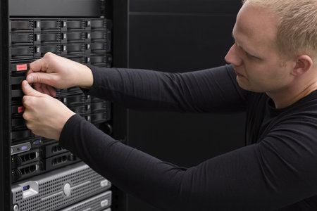 It engineer   technician working in a data center  This enclosures is a SAN  storage area network ...
