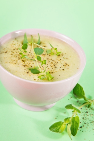 Fresh and delicious cauliflower and broccoli soup on green background  Oregano and pepper on top and on the side の写真素材