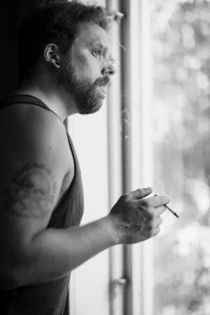 Punk rocker standing by the window, smoking cigarettes and thinking の写真素材