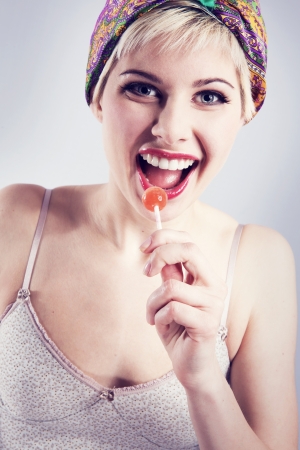 Happy vintage looking young woman with a lollipop の写真素材