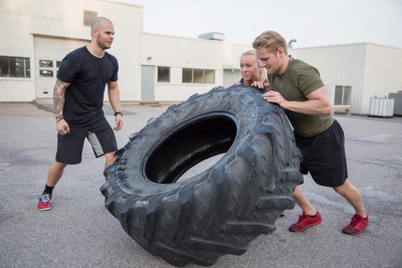 A group or team flipping heavy tires outdoor. Men and women workout.の写真素材