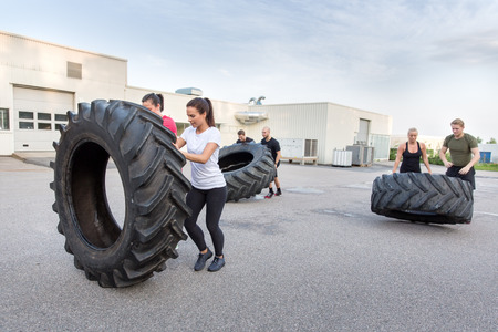 Fitness team flipping heavy tires as workoutの写真素材
