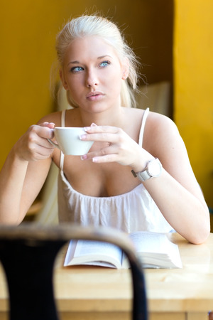 Young blonde woman drinking coffee at cafeの写真素材