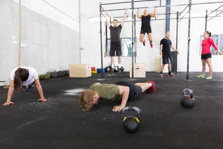 Training push ups, hang ups and squat at a fitness gym center. Group workout.の写真素材