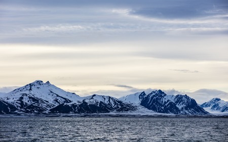 Clouds over mountains covered with snow in the cold arctic environment in Svalbard.の写真素材