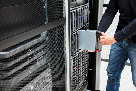 Midsection of male computer engineer installing blade server in chassis at data center