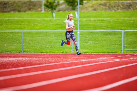 Full length of determined young woman running on sports tracks