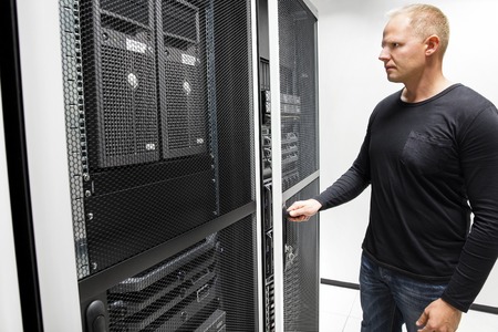 Mid adult male technician opening server rack door in large data centerの写真素材