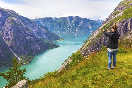 Woman hiking tourist in the high norwegian mountains over a beautiful fjord.の写真素材