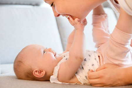 Happy and caring mother laughing together with her child. Smiling and cute young baby girl.