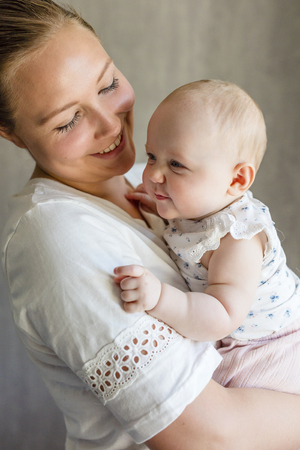 Cute baby girl with her smiling and caring motherの写真素材