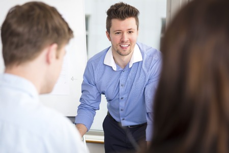 Businessman Smiling While Looking At Colleagues In Officeの写真素材