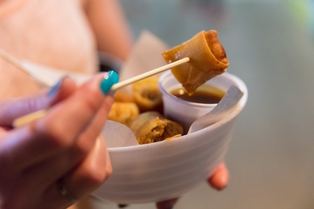 Woman Having Spring Rolls At Food Stallの写真素材