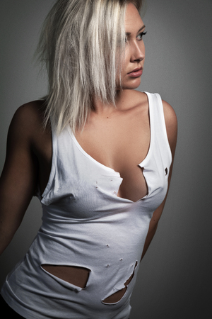 Studio portrait of beautiful blonde woman with worn holey t-shirtの写真素材