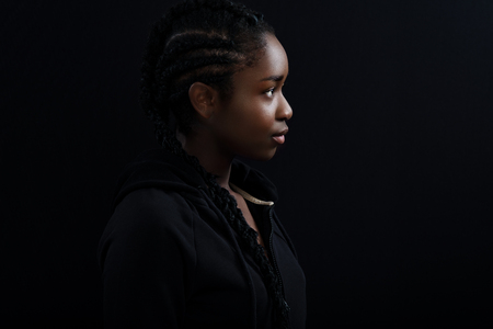 Cool and beautiful Black Female Model Looking Away Against Black Backgroundの写真素材