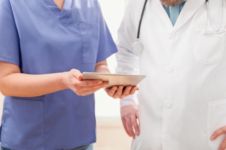 Doctors discussing report about a patient at tablet computer in hospitalの写真素材