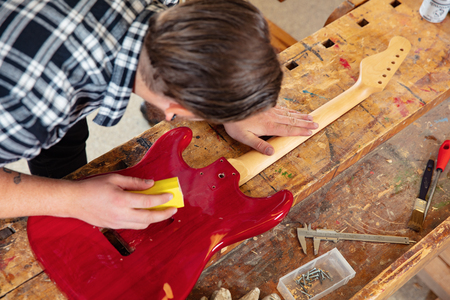 Top view of craftsman sanding a guitar neck in wood at workshopの写真素材