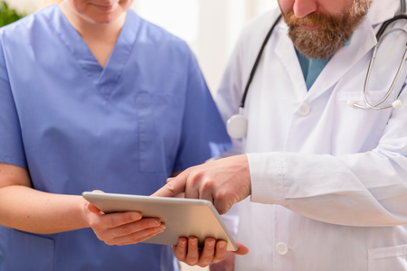 Doctor and nurse discussing patients tests at tablet computer in hospitalの写真素材