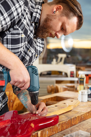 Portrait of craftsman working in workshop with guitarの写真素材