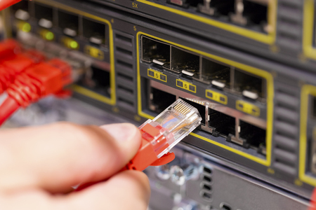 IT consultant connects a network cable into switch in datacenterの写真素材