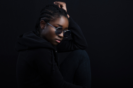 Cool african woman sitting with dark skin wearing round sunglassesの写真素材