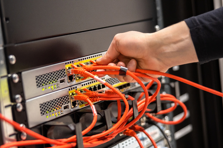 Close-up of Male Technician Plugging Network Cable In Network Routerの写真素材