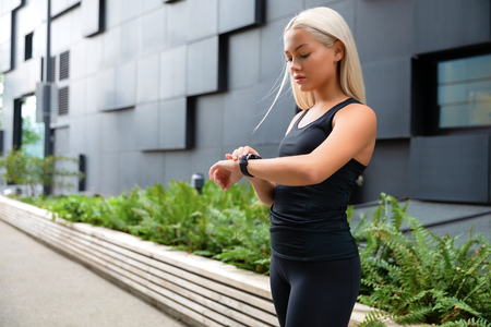 Woman checking her fitness smart watch device in urban environmentの写真素材