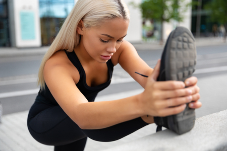 Gorgeous young Woman Doing Stretching Exercise At Sidewalk In Cityの写真素材