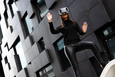 Dedicated Woman Wearing Virtual Reality Technology Glasses Against Buildingの写真素材