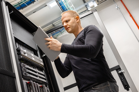 Male Technician Using Digital Tablet In Datacenter to Monitor SAN and Serversの写真素材