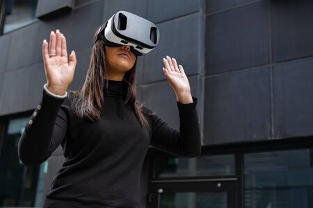 Woman Playing With Virtual Reality Glasses Against Futuristic Wallの写真素材