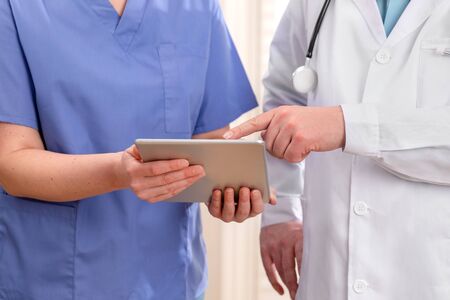 Doctor and nurse discussing patients tests at tablet computer in hospitalの写真素材
