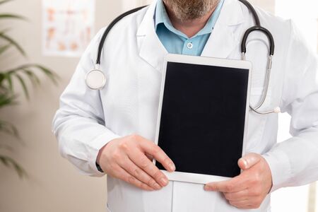 Adult male doctor showing a digital image or report on a tabletの写真素材