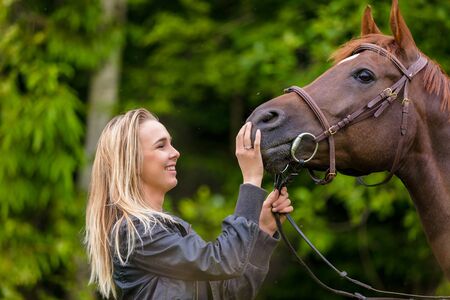 Close-up of smiling woman feeding her arabian horse with snacksの写真素材