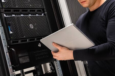 Close-up of IT Consultant Holding Digital Tablet Analyzing Serversの写真素材
