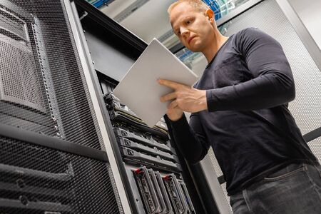 Male IT Engineer Using Tablet In Datacenter to Monitor Network and Serversの写真素材