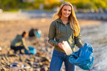 Volunteer holding bottle and garbage bag at beachの写真素材
