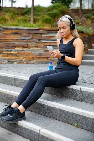Sporty Young Woman Listening Music With Headphones And Smartphoneの写真素材